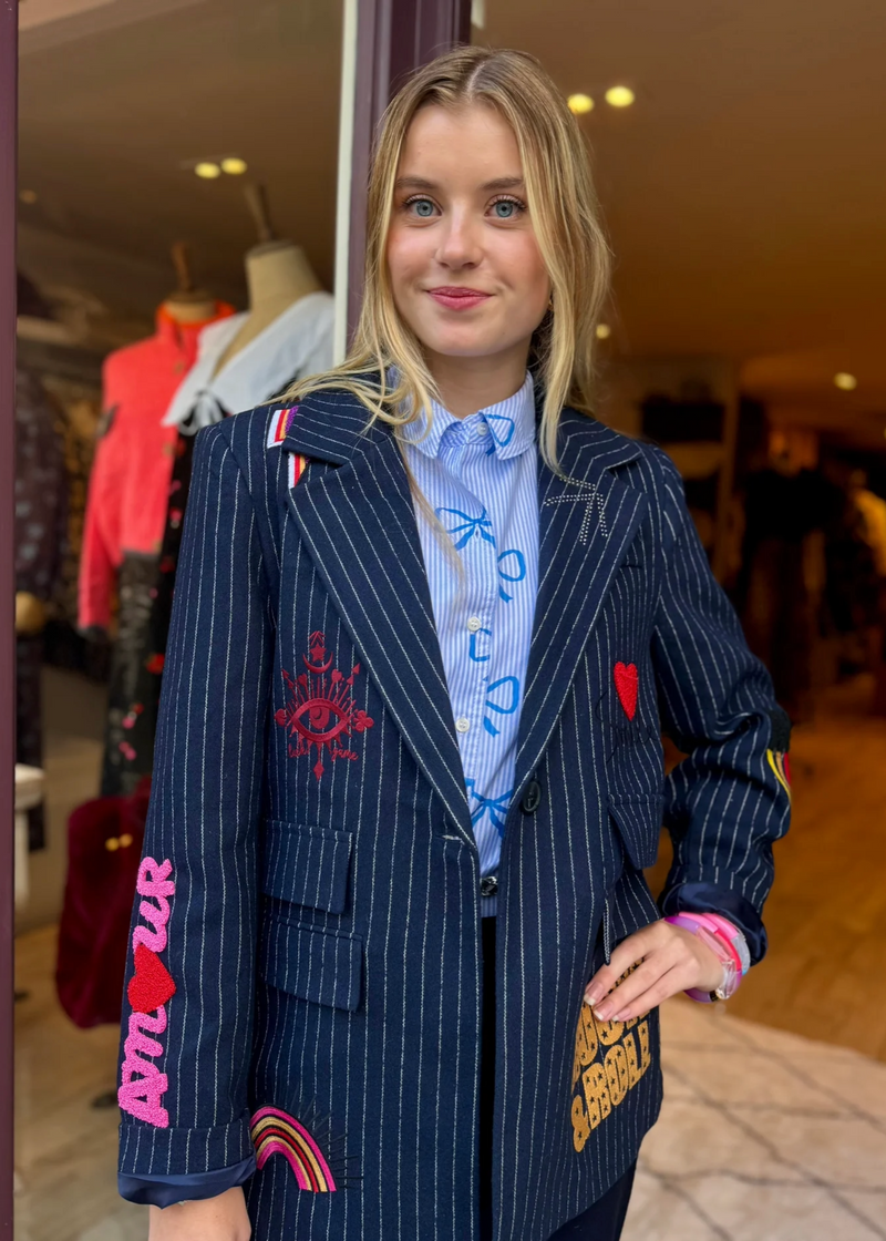 woman wearing navy pinstripe blazer with cool patches on 