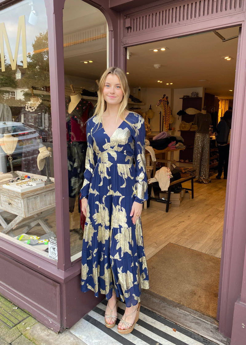 woman wearing a navy blue and gold maxi dress with a floral print